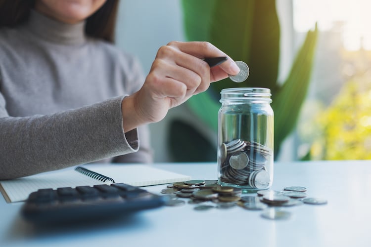 Woman putting money into a jar